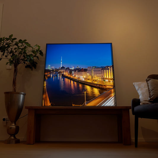 Gerahmtes LED-Bild mit nächtlicher Skyline über dem Fluss und Lichterkette am Ufer