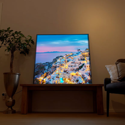 LED-Bild „Santorini bei Nacht“ im Rahmen, warm leuchtende Häuser am Meer bei Dämmerung