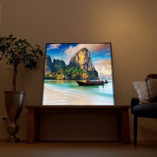 LED-Bild: Strand und Boot bei Sonnenaufgang, Berge im Motiv, schwarzer Rahmen