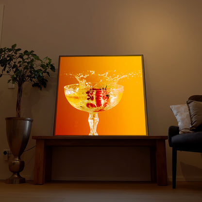 Gerahmtes LED-Bild mit Glas Orangensaft und Spritzern auf orangefarbenem Hintergrund
