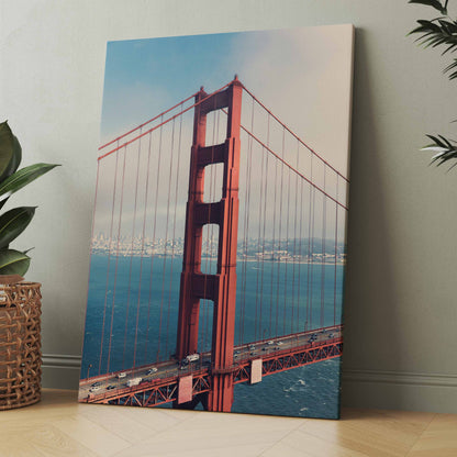 Leinwandbild mit roter Hängebrücke über blauem Wasser und Himmel